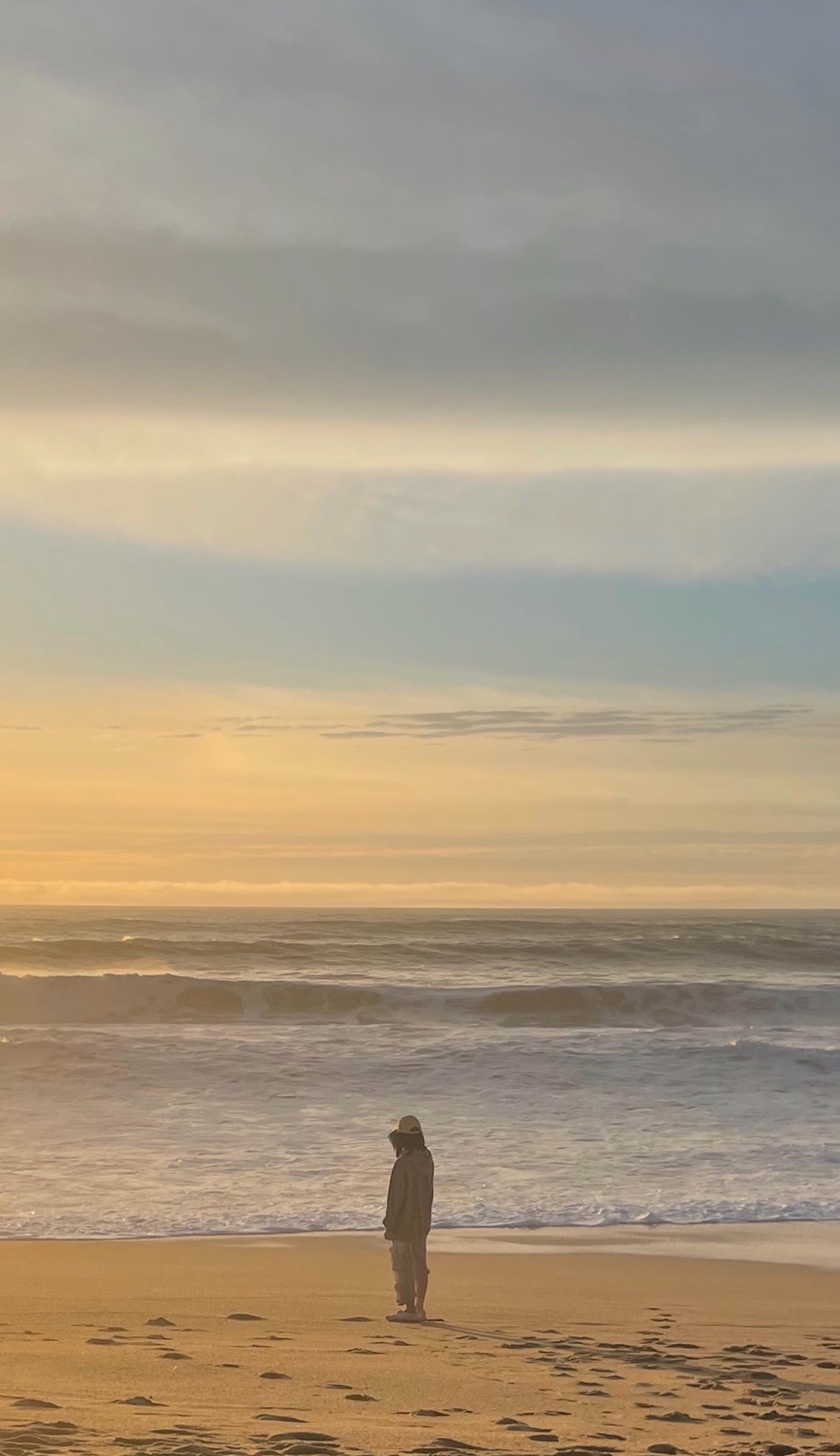 A person standing on the beach at sunset in Half Moon Bay, California